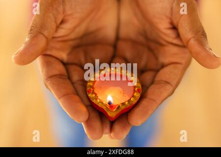 Tenant diya décoratif, mains montrant la lumière traditionnelle du festival indien diwali Banque D'Images