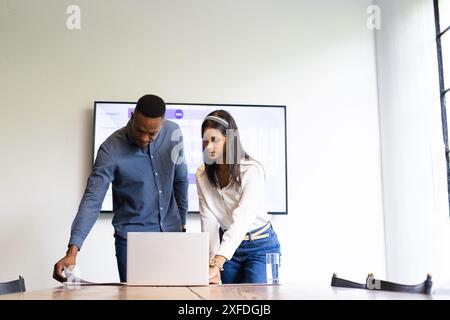 Collaborer sur un projet, les collègues examinent des documents et utilisent un ordinateur portable au bureau Banque D'Images