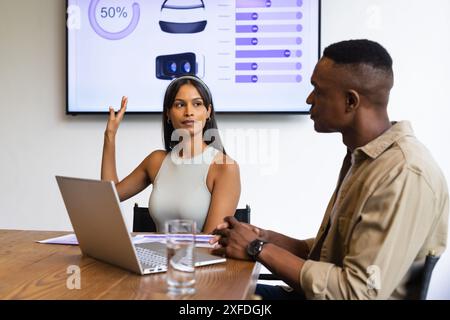Présentation des données, femme avec ordinateur portable discutant du projet avec un collègue en réunion Banque D'Images