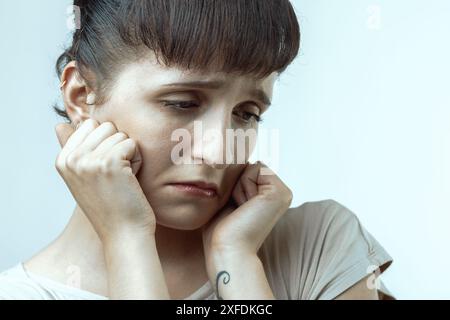 Une jeune femme troublée est aux prises avec des émotions, cherchant à surmonter la tristesse et le désespoir dans un portrait rapproché montrant la solitude et l'anxiété Banque D'Images