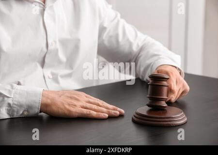 Avocat masculin avec marteau de juge assis près de la table dans le bureau, gros plan Banque D'Images