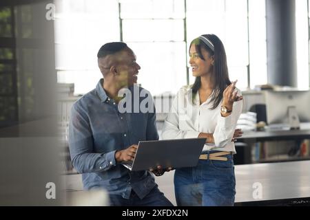Collaboration au bureau, collègues discutant de projet tout en utilisant un ordinateur portable ensemble Banque D'Images