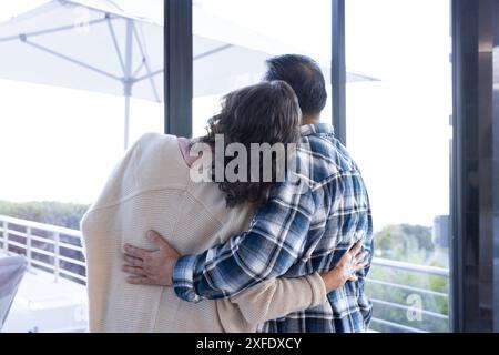 Couple senior embrassant et regardant par la fenêtre, profitant de vacances ensemble Banque D'Images