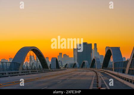 Vue captivante sur l'emblématique viaduc de la 6e rue à Los Angeles au coucher du soleil, avec l'architecture dynamique de la ville silhouette contre les teintes chaudes de Banque D'Images