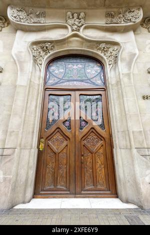 Espagne, Catalogne, Barcelone, porte avec un vitrail sur le panneau de tableau arrière et façade avec des sculptures représentant une famille avec un enfant et f Banque D'Images