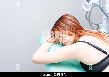 Une femme dort sur un oreiller vert. Elle porte un soutien-gorge noir Banque D'Images