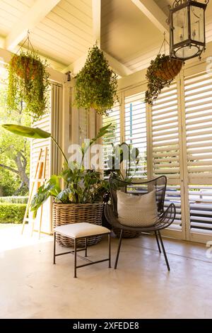 Jardin intérieur avec plantes suspendues et chaise en osier dans la pièce ensoleillée, espace copie Banque D'Images