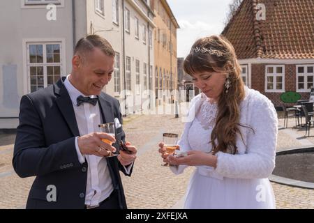 La mariée et le marié après la cérémonie tiennent une coupe de champagne dans leurs mains. Célébration de l'occasion. Mariage Banque D'Images