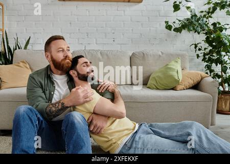 Deux hommes barbus se détendent sur un canapé, profitant de la compagnie de l'autre dans un salon chaleureux. Banque D'Images