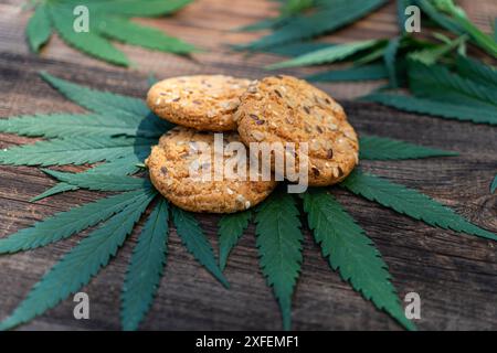 Feuille de marijuana et bonbons sur table en bois. Fleurs de cannabis et biscuits de près. Récréation de chanvre, cuisine canna, passe-temps, concept de légalisation. Banque D'Images