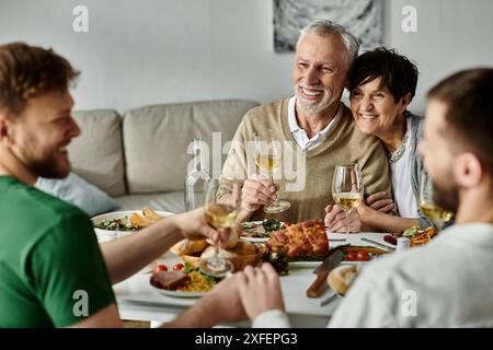 Un couple gay profite d’un dîner en famille, partageant un moment chaleureux et affectueux. Banque D'Images