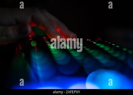 Gros plan main jouant au jeu en ligne avec clavier et pc. clavier led rgb coloré Banque D'Images