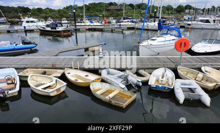 Port de Lymington, Angleterre. 18 juin 2024. Vue à grand angle de petits bateaux à rames et radeaux alignés le long d'une passerelle en bois. Banque D'Images