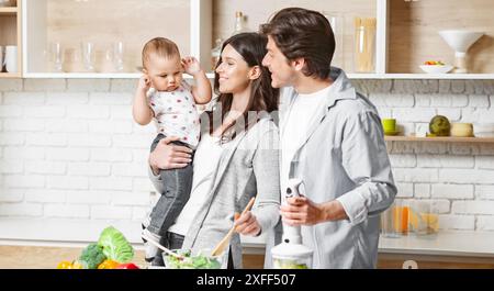 Famille heureuse préparant la nourriture ensemble dans leur cuisine Banque D'Images