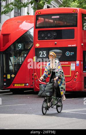 Une banlieue colorée portant des vêtements à la mode est assise sur son vélo de ville Brompton parmi la circulation sur Aldwych, centre de Londres, Angleterre, Royaume-Uni Banque D'Images