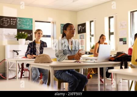 Au lycée, les adolescents utilisent des ordinateurs portables et écoutent attentivement en classe Banque D'Images