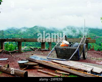 Des piles de bois de construction restantes ont été laissées avec divers outils pour travailler sur un chantier de construction rural. Banque D'Images