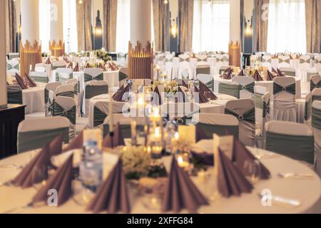 Réception sophistiquée avec tables décorées et éclairage moderne dans une salle de banquet Banque D'Images