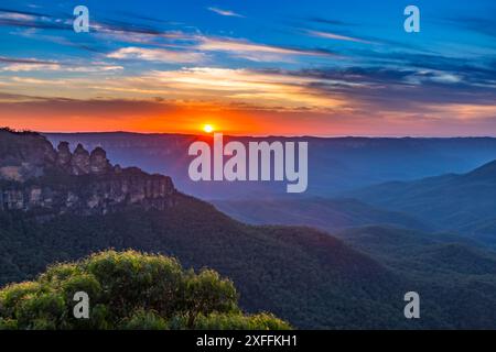 Un coucher de soleil éclatant illumine la formation rocheuse emblématique des Three Sisters dans le parc national des Blue Mountains en Australie. Banque D'Images