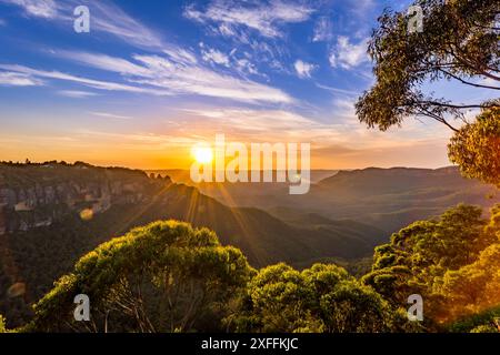 Un coucher de soleil éclatant illumine la formation rocheuse emblématique des Three Sisters dans le parc national des Blue Mountains en Australie. Banque D'Images