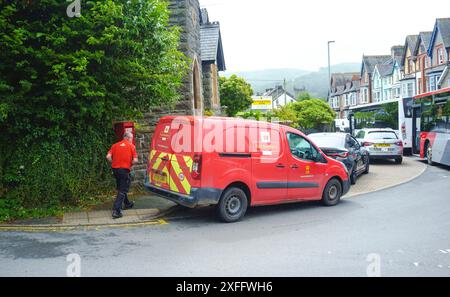 Un facteur marche vers une camionnette Royal mail garée dans une rue de Machynlleth, Ceredigion, pays de Galles. Banque D'Images