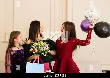 Femme tenant des fleurs, célébrant avec deux filles à la fête d'anniversaire. Du temps en famille ensemble Banque D'Images