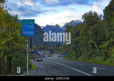 Route principale dans la petite ville de Franz Josef sur l'île du Sud de Nouvelle-Zélande. Les montagnes enneigées et le glacier peuvent être vus au loin Banque D'Images