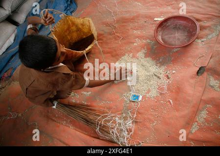 Un garçon ramasse les restes de riz au marché de gros de Badamtoli dimanche, incapable de se permettre les produits essentiels à cause de la flambée des prix. 06 avril 2008 Banque D'Images