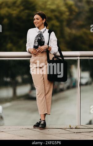 Une femme d'affaires latina souriante marche avec confiance dans les rues urbaines. Banque D'Images