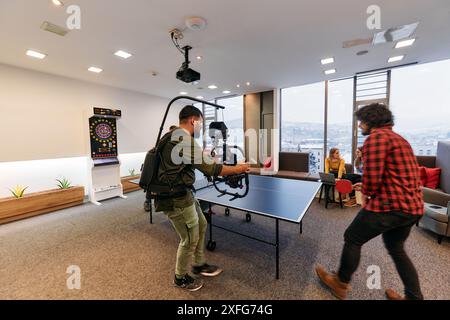 Le vidéaste capture des collègues d'affaires jouant au tennis de table pendant la pause Banque D'Images