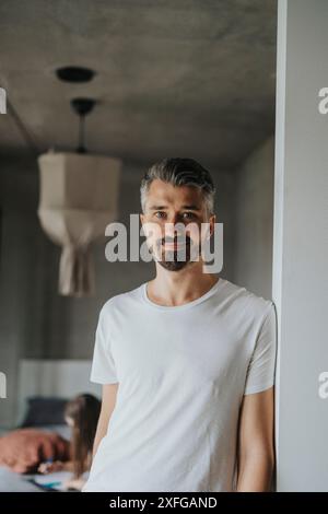 Portrait d'homme souriant avec la barbe appuyée sur le mur à la maison Banque D'Images
