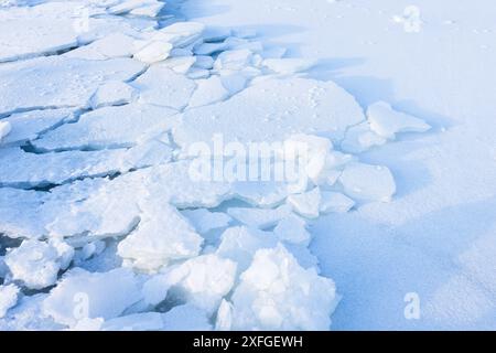 Des hummocks de glace craquelés couverts de neige blanche. Des fragments de glace brisée gisaient sur la côte gelée de la mer Baltique par une journée d'hiver ensoleillée Banque D'Images