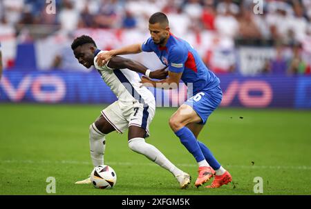 GELSENKIRCHEN, ALLEMAGNE - JUIN 30 : Bukayo Saka, d'Angleterre, affronte David Hancko, de Slovaquie, lors de la manche 16 de l'UEFA EURO 2024 opposant l'Angleterre et la Slovaquie à l'Arena AufSchalke le 30 juin 2024 à Gelsenkirchen, Allemagne.© diebilderwelt / Alamy Stock Banque D'Images