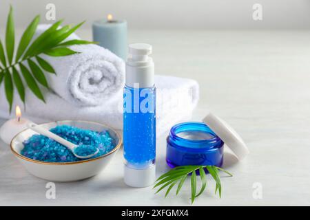 Composition pour spa. Produits cosmétiques, serviettes, sel de mer et bougies allumées sur la table lumineuse Banque D'Images