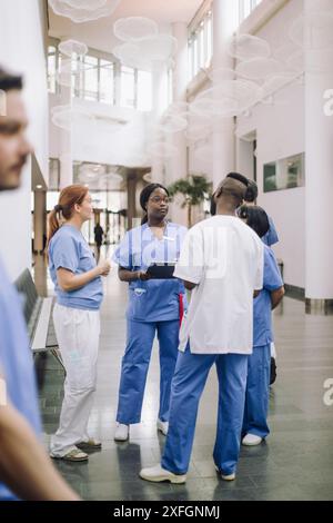 Professionnels de la santé multiraciaux masculins et féminins discutant dans le hall de l'hôpital Banque D'Images