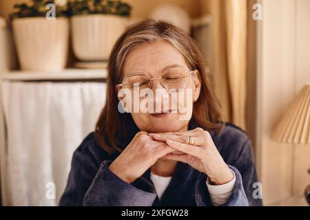 Femme âgée souriante avec les yeux fermés à la maison Banque D'Images