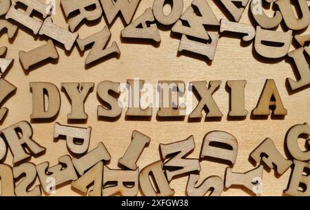 Dyslexie, mot en lettres de l'alphabet en bois entouré de lettres aléatoires sur fond de bois Banque D'Images