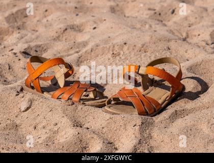 Enfants, chaussures orange sur la plage. Sable. Mer. Repos. Vacances. Banque D'Images