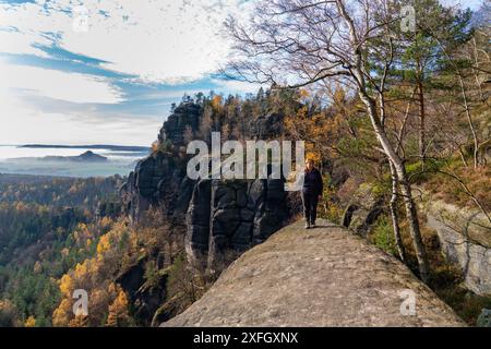 Une femme d'âge moyen parcourt le monde. Se dresse sur fond de montagnes majestueuses dans le parc national de Saxe, Bastei, Suisse, Allemagne. Banque D'Images