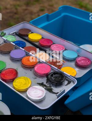 Boîtes et tubes de peinture colorés avec peintures sur une table. Peintures et pinceaux pour maquillage, pour la peinture sur les visages, la peinture sur le visage, l'art du visage Arrière abstrait Banque D'Images