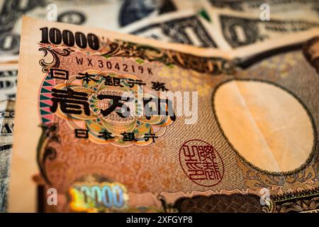 3 juillet 2024, Tokyo, Japon : images d'un billet de 10 000 yens et de billets de 1 dollar américain. Le yen japonais a récemment chuté à son plus bas niveau en 37 ans, tombant en dessous de 160 par rapport au dollar américain. Cette importante dépréciation est la plus faible que le yen ait connue depuis 1986, ce qui a conduit à des attentes accrues d’intervention des autorités japonaises sur le marché. La baisse du yen, qui a atteint 160,82 lors des échanges, a suscité des inquiétudes et des spéculations sur les actions potentielles du ministère japonais des Finances pour stabiliser la monnaie. Cette situation fait suite à des interventions précédentes plus tôt cette année, où Japan sp Banque D'Images