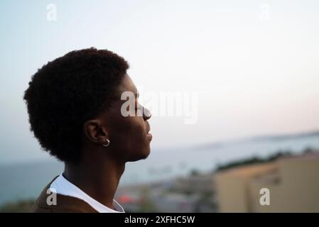 Jeune homme avec les yeux fermés au coucher du soleil Banque D'Images