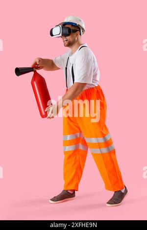 Pompier masculin avec extincteur utilisant des lunettes VR sur fond rose Banque D'Images