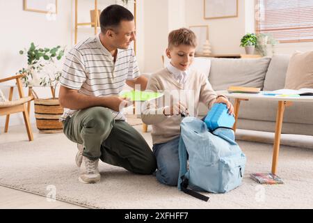 Petit garçon avec son père emballant la boîte à lunch de l'école dans le sac à dos à la maison Banque D'Images