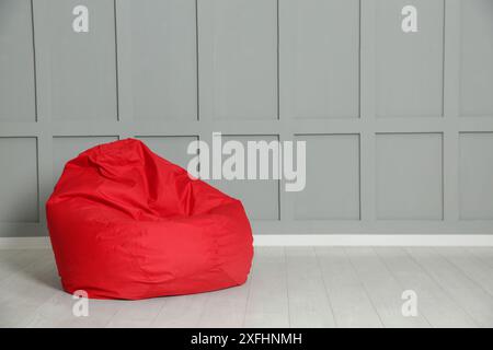 Chaise de sac de haricot rouge près du mur gris à l'intérieur. Espace pour le texte Banque D'Images