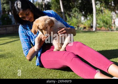 Assis sur l'herbe, femme tenant et jouant avec adorable chiot à l'extérieur Banque D'Images