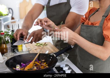 Cuisiner ensemble, couple préparant des légumes au wok dans une cuisine moderne Banque D'Images