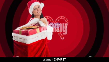 Image de femme dans la tenue de père noël avec sac de cadeaux de noël sur des cannes de bonbons sur des cercles rouges Banque D'Images