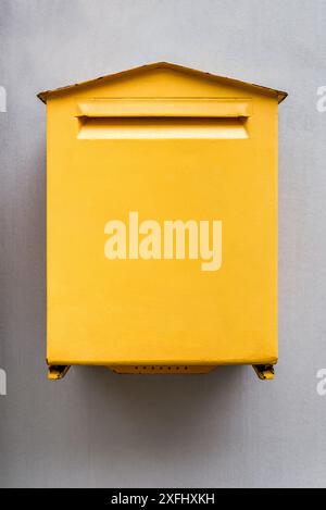 Maquette d'une vieille boîte aux lettres rectangulaire jaune vierge sur mur de béton beige en gros plan. Vue de face Banque D'Images