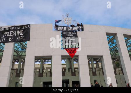 04 juillet 2024, Australie, Canberra, Parlement. Un manifestant pro-palestinien monte sur le toit du Parlement australien pour déployer des banderoles critiquant le rôle du gouvernement australien dans la facilitation du génocide à Gaza Banque D'Images